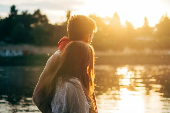 A couple watching the sunset by a lake